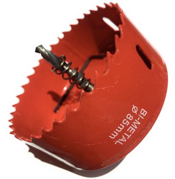 Close-up of a red hole saw attachment with serrated rim and central spiral drill bit